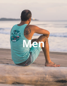 Man sitting on the beach wearing a blue tank top and matching boardshorts from the Hamabe brand, enjoying a relaxed seaside moment. 