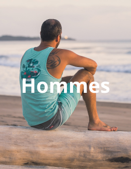 Homme assis sur la plage, v&ecirc;tu d&rsquo;un d&eacute;bardeur bleu et d&rsquo;un boardshort assorti de la marque Hamabe, profitant d&rsquo;un moment de d&eacute;tente au bord de la mer. 